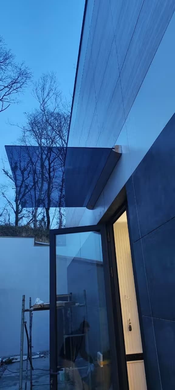 Козырек из стекла в зажимном профиле над входом в частном доме в Адлере, Сочи — производство и установка под ключ